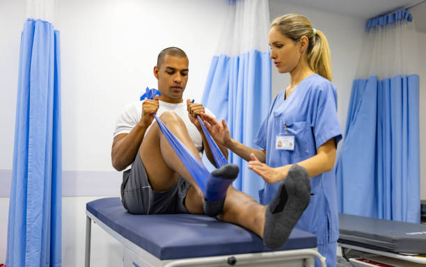 Male patient doing physical therapy exercises with the guidance of his therapist and using a resistance band